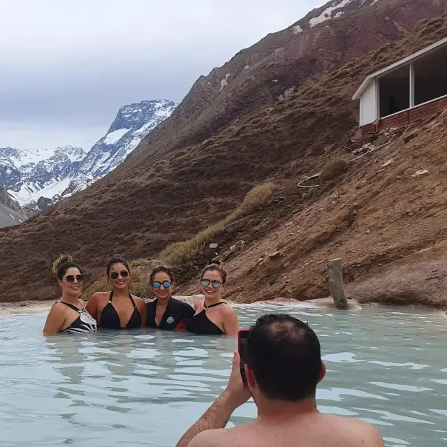 Piscina termal turquesa con una cascada sobre formaciones de travertino