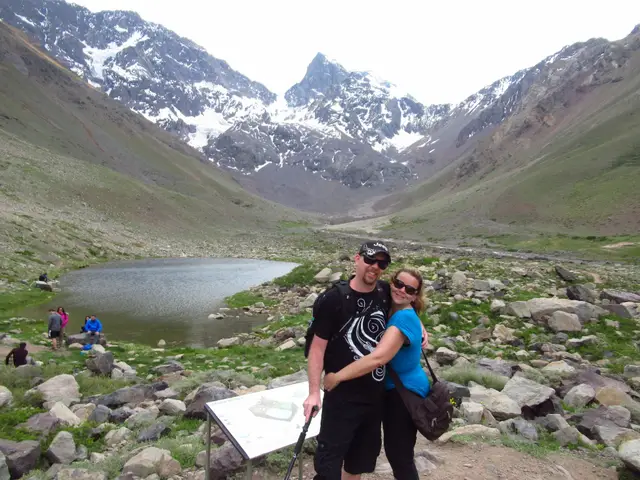 Pareja abrazada junto a la laguna con el valle y las montañas de fondo
