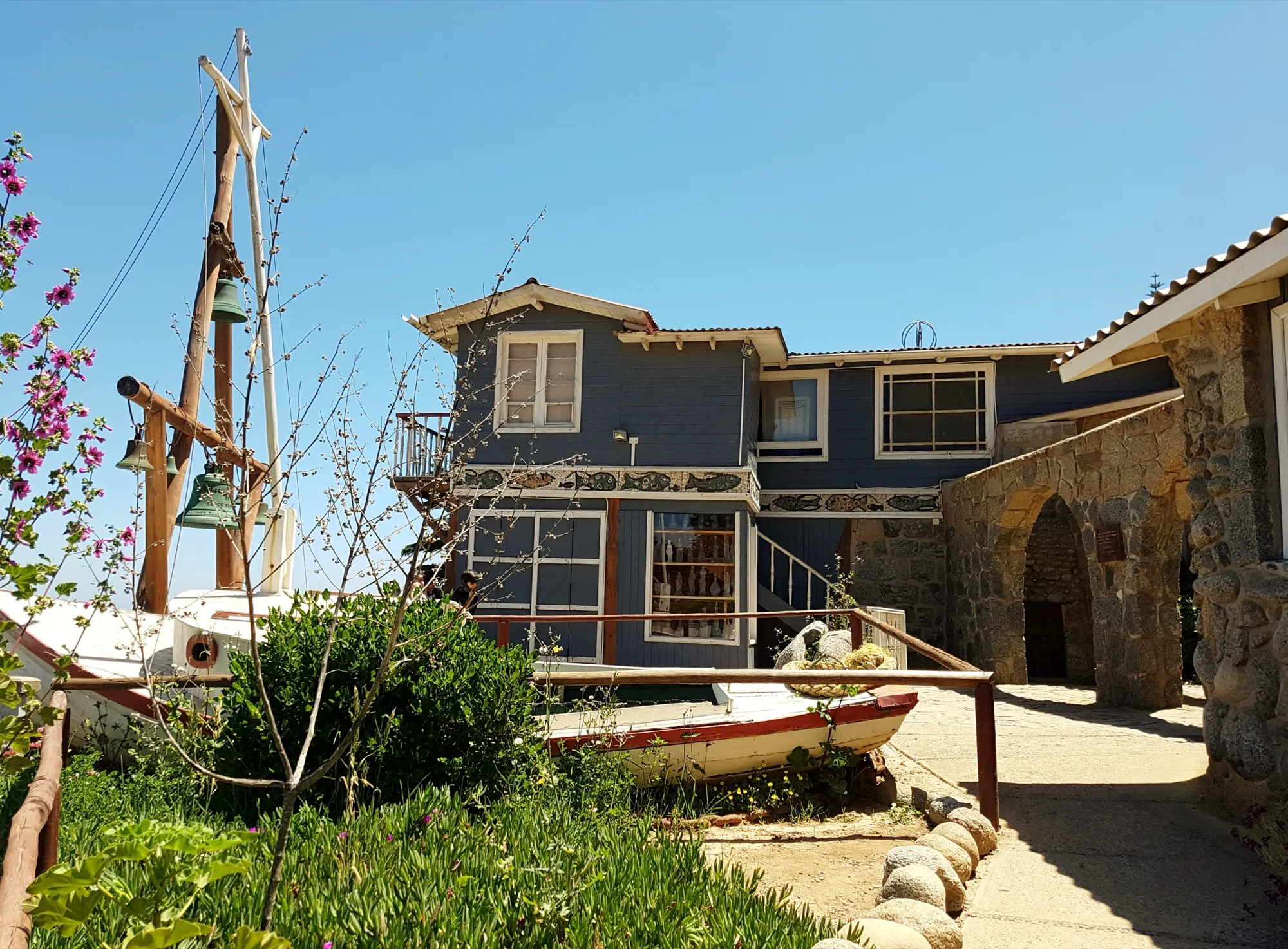 Casa Museo de Isla Negra, de madera azul grisácea, con un bote y un mástil en primer plano