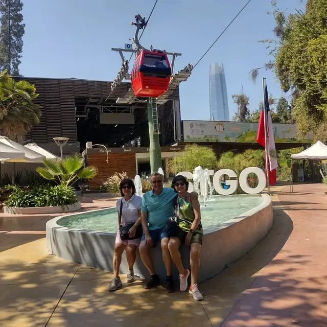 Familia sentada junto a la fuente y las letras STGO con el teleférico detrás