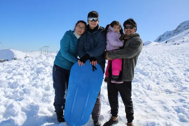 Familia posando con un trineo en la nieve del Parque Farellones