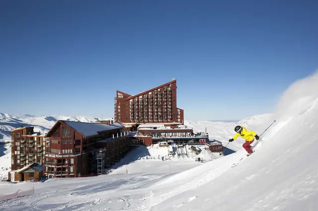 Esquiador bajando una pista frente al hotel de Valle Nevado