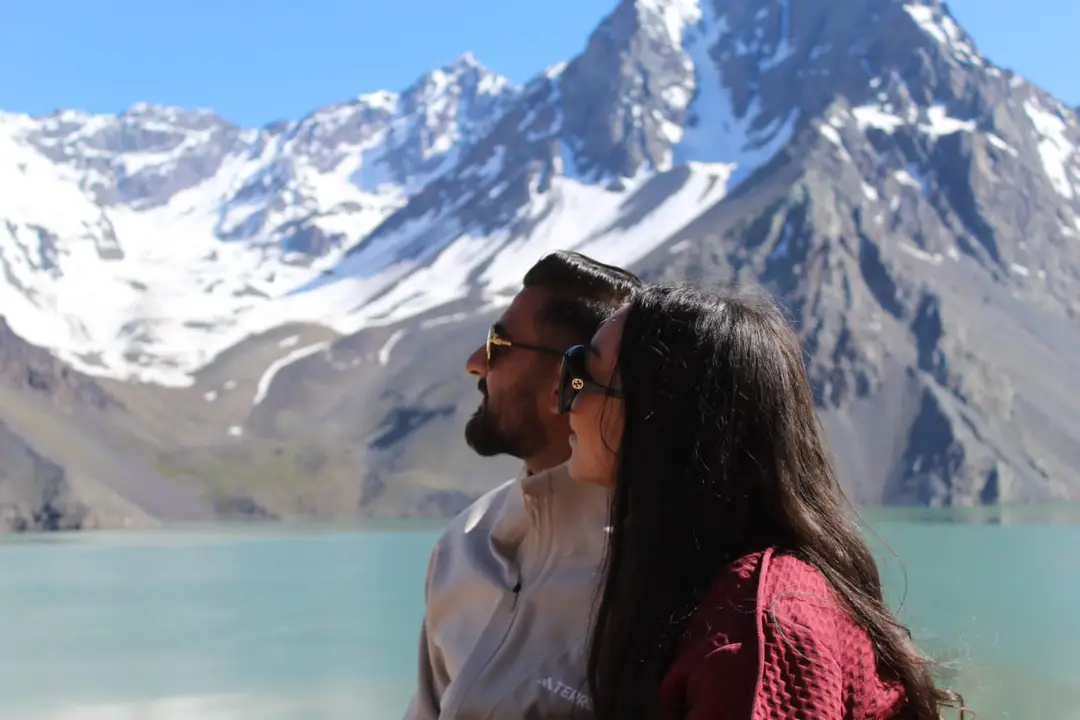 Pareja mirando el Embalse El Yeso, con montañas nevadas al fondo