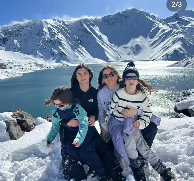 Familia sentada en la nieve frente al embalse El Yeso