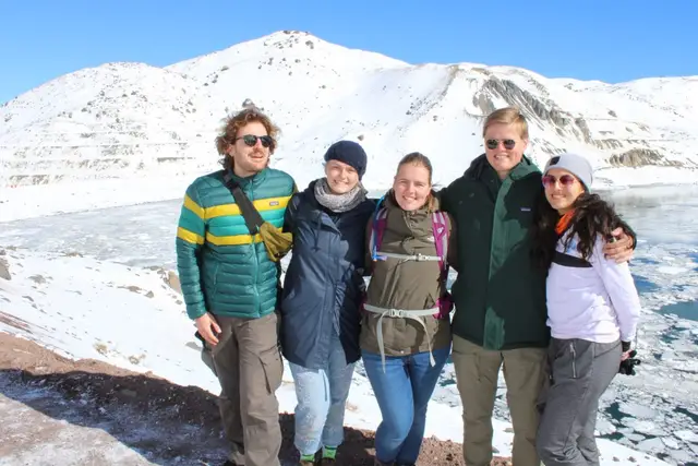 Grupo de cinco viajeros abrazados junto al embalse en la nieve