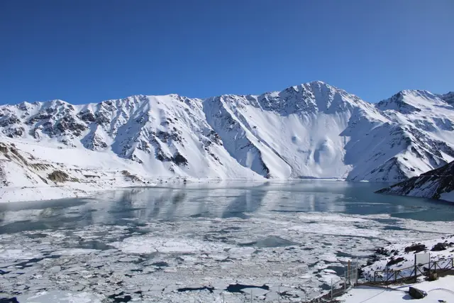 Embalse El Yeso con el lago parcialmente helado y las montañas nevadas