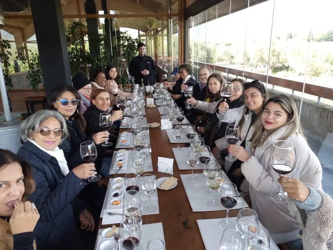 Grupo de viajeros brindando con copas de vino en una mesa larga durante una cata