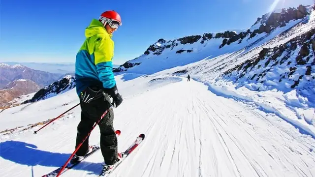 Esquiador bajando una pista de La Parva con vista al valle