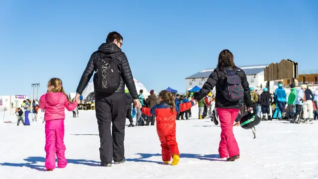 Familia caminando de la mano sobre la nieve en el Parque Farellones