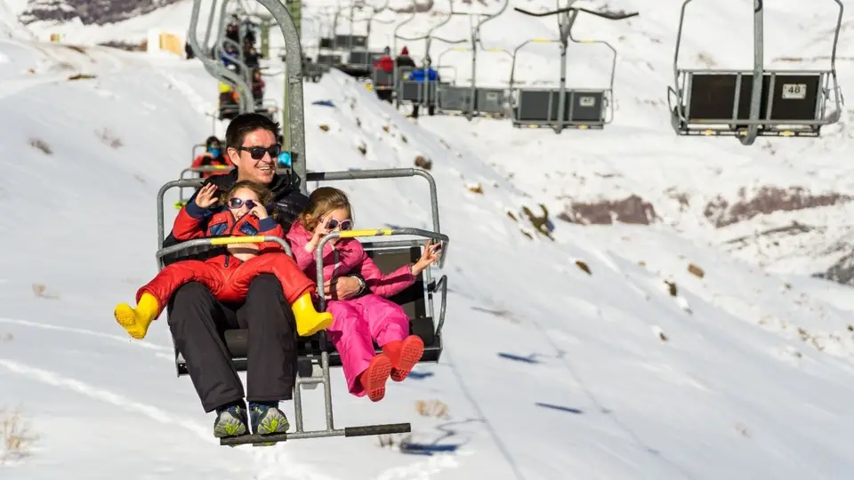 Familia en un telesilla sobre la nieve en un centro de esquí cerca de Santiago