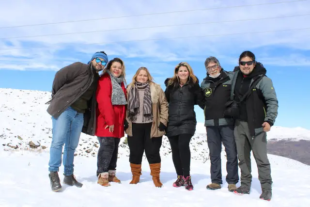Grupo de seis personas posando en la nieve con la cordillera de fondo