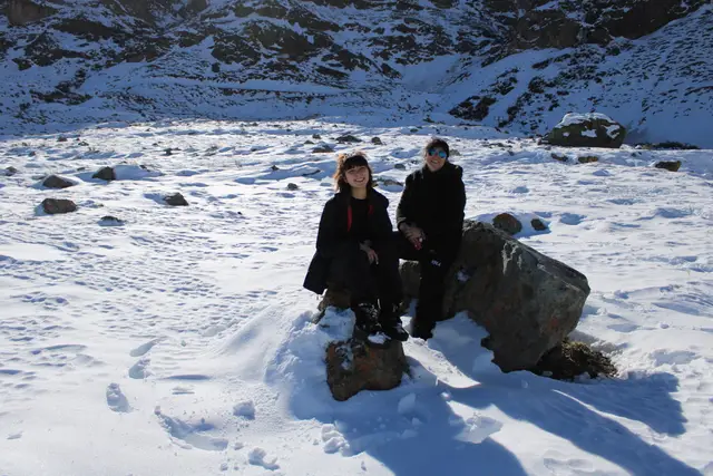 Pareja sentada sobre una roca en la nieve de la cordillera