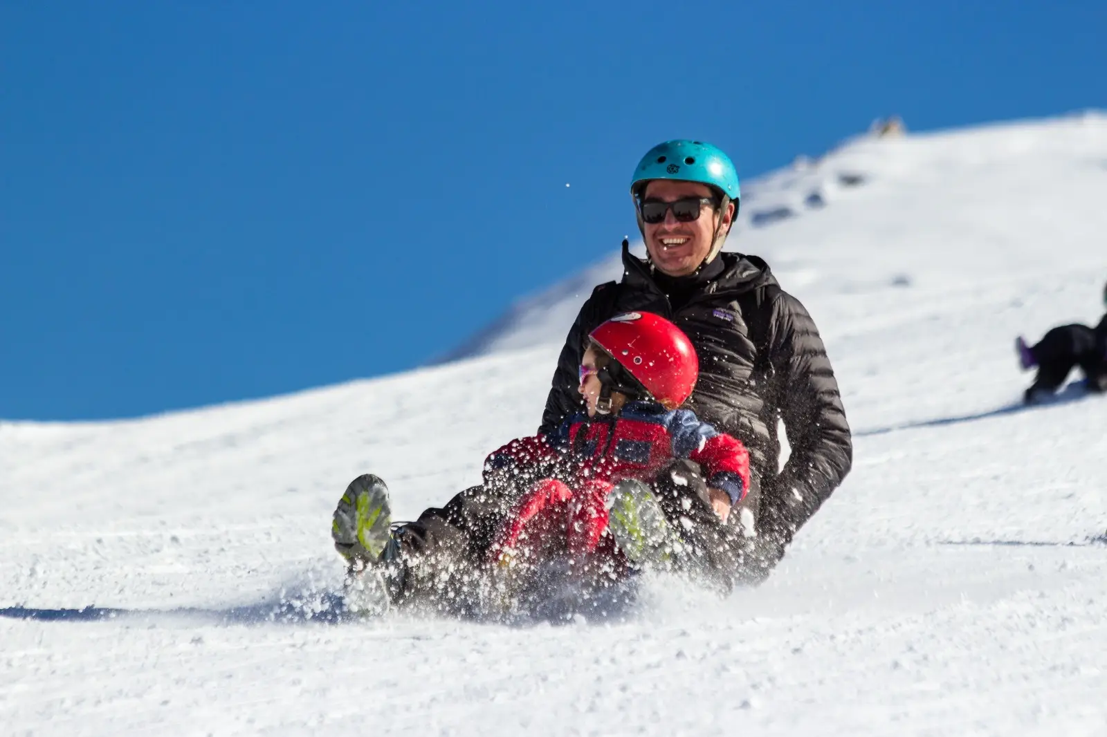 Familia bajando en trineo por la nieve en el Parque Farellones