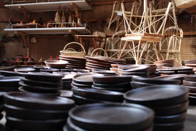 Estantes con platos de cerámica y cestas de mimbre en una tienda de artesanía de Pomaire