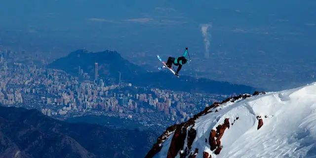 Snowboarder saltando en La Parva con Santiago de fondo