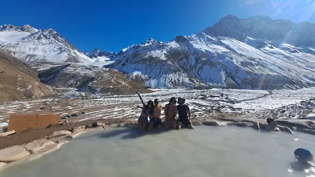 Pareja en las aguas termales de colina con el fondo de montañas nevado