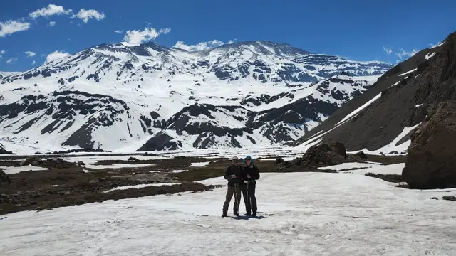 Excursionistas caminando sobre un campo de nieve en la cordillera