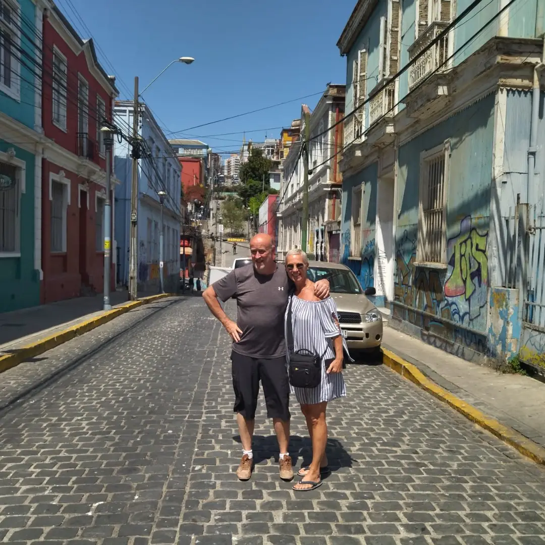 Pareja en una calle con grafitis y casas de colores en Valparaíso